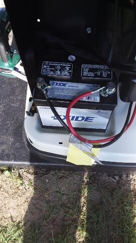 A Car Battery Labeled &Quot;Exide&Quot; With Red And Black Cables Connected, Sits Snugly In The Vehicle Compartment. In Case Of Emergencies, A Generac Generator Provides Backup Power Seamlessly.