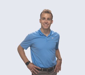 Person In A Blue Polo Shirt And Dark Pants, Smiling With Hands On Hips Against A Light Background. Ready To Meet The Team, Their Confident Pose Invites Camaraderie And Collaboration.