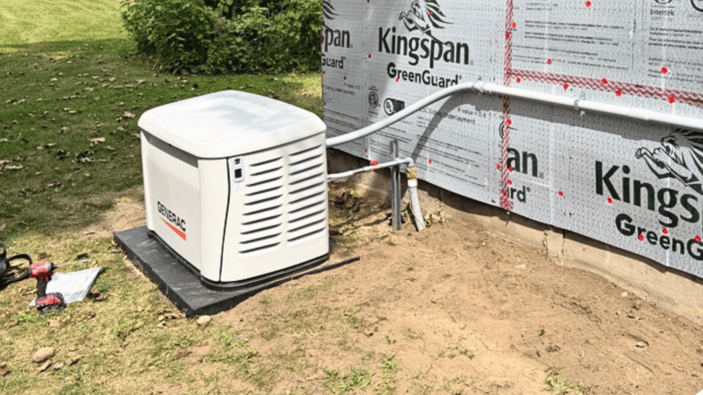 Is A Whole-Home Generator Really Worth It For Frequent Power Outages? | Grand Bay Electrical A Standby Generator Is Installed On A Concrete Pad Next To A House Under Construction With Greenguard Insulation Visible On The Exterior Wall.